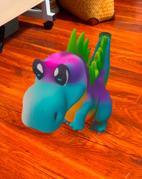 A Drawings Alive 3D dinosaur standing on a wooden floor in augmented reality